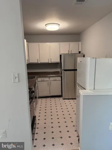a kitchen with a refrigerator a stove top oven and cabinets