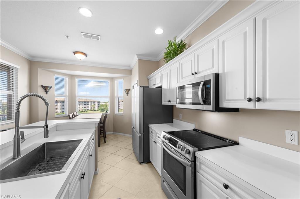 8570 Kingbird Loop, Unit 547 Estero, FL 33967 - Photo 5 of 50 a kitchen with stainless steel appliances granite countertop a kitchen island a stove a sink and a microwave