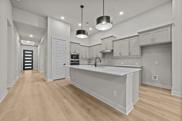 a large kitchen with stainless steel appliances a large counter top and a wooden floors
