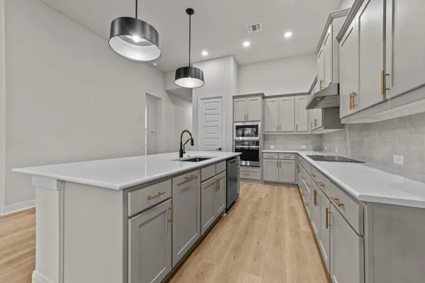 a kitchen with stainless steel appliances granite countertop a sink a stove and a wooden floors