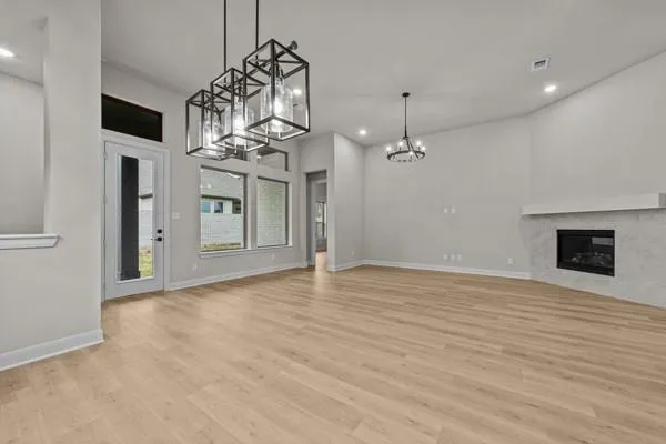 a view of a livingroom with a chandelier fan and kitchen view