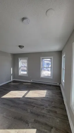 a view of empty room with window and wooden floor