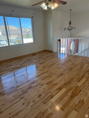 1259 West Raintree Drive Price, UT 84501 - Photo 5 of 10 Empty room with a ceiling fan, light wood-style floors, and a chandelier