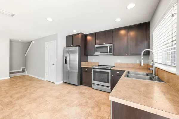a kitchen with stainless steel appliances granite countertop a stove a sink and a refrigerator with wooden floor