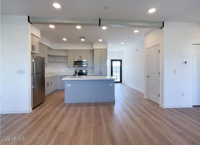 a large kitchen with stainless steel appliances a large counter top and wooden floors