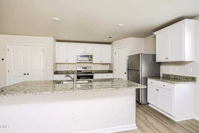 a kitchen with granite countertop a refrigerator stove top oven and sink