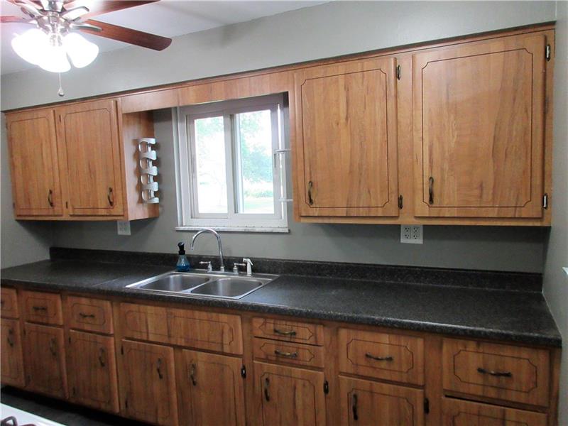This bright kitchen features new vinyl floor, plaster walls, a new lighted ceiling fan and additional light fixtures.