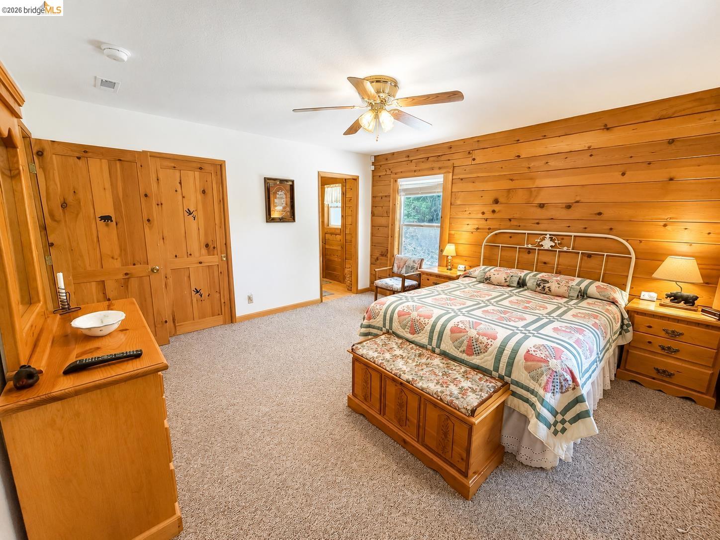 21181 Phoenix Lake Road Sonora, CA 95370 - Photo 23 of 34 Interior room featuring wood-paneled accent wall, neutral-toned carpeting, and a ceiling fan with integrated lighting
