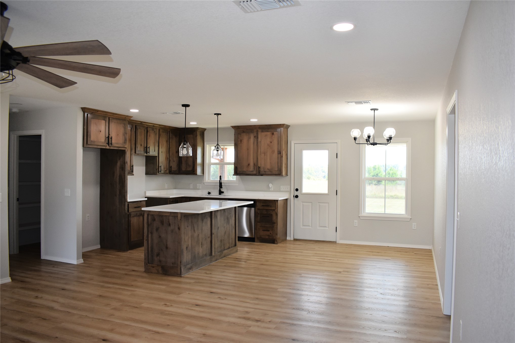 2915 East 2090 Road Hugo, OK 74743 - Photo 2 of 27 Open concept living space featuring wood-finish flooring, recessed lighting, a ceiling fan, and a kitchen with wood cabinetry, a central island, and stainless steel appliances