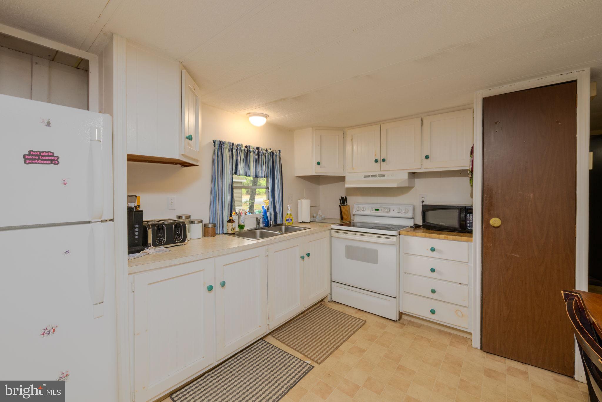 27284 Cottage Road, Unit 9182 Millsboro, DE 19966 - Photo 7 of 18 a kitchen with white cabinets and white appliances
