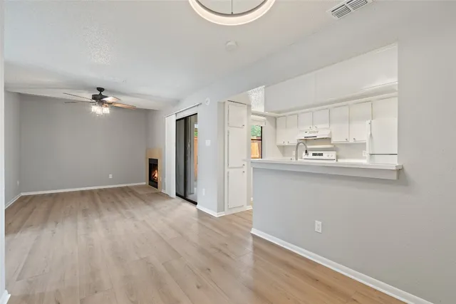 a view of kitchen and empty room with wooden floor