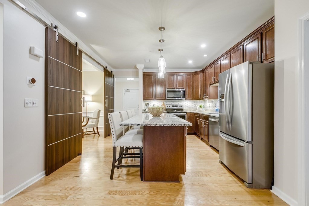 a kitchen with stainless steel appliances a refrigerator a stove a sink dishwasher and a refrigerator with wooden floor