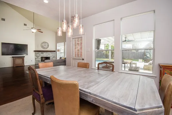 a dining room with wooden floor a chandelier a wooden table and chairs