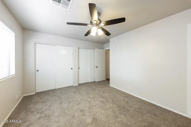 an empty room with windows and fan