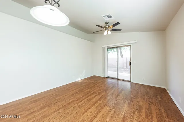 an empty room with wooden floor fan and windows