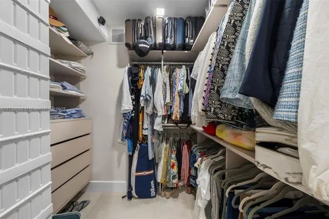 a view of walk in closet with clothes and shoes