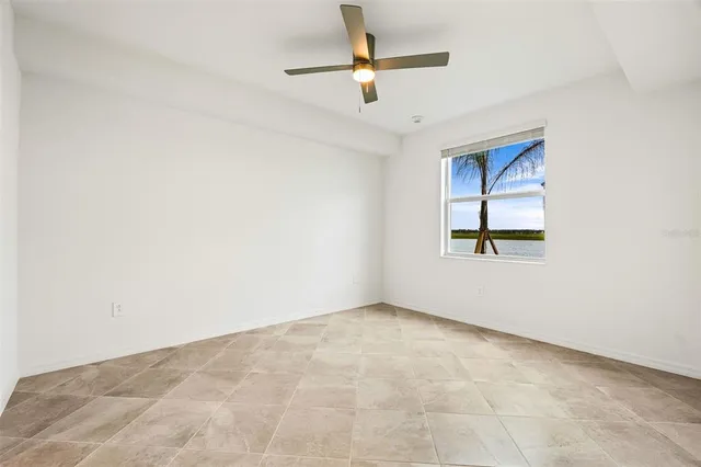 an empty room with chandelier fan and windows