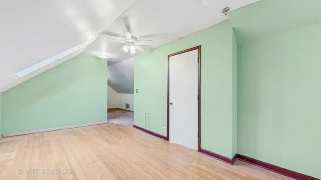 a view of an empty room with wooden floor and a ceiling fan