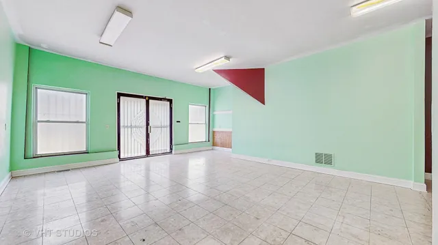 a view of an empty room with a window and a kitchen