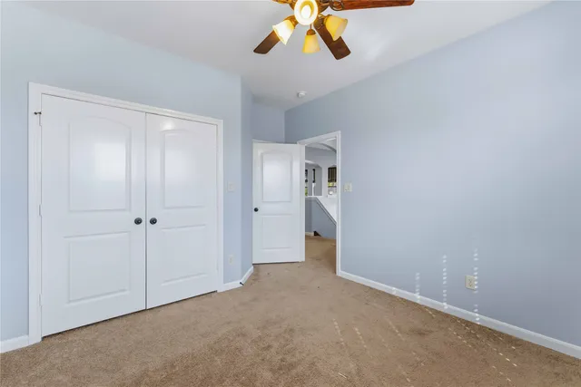 an empty room with windows and chandelier fan