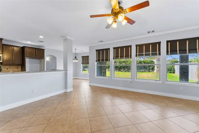 a view of an empty room with window and kitchen view