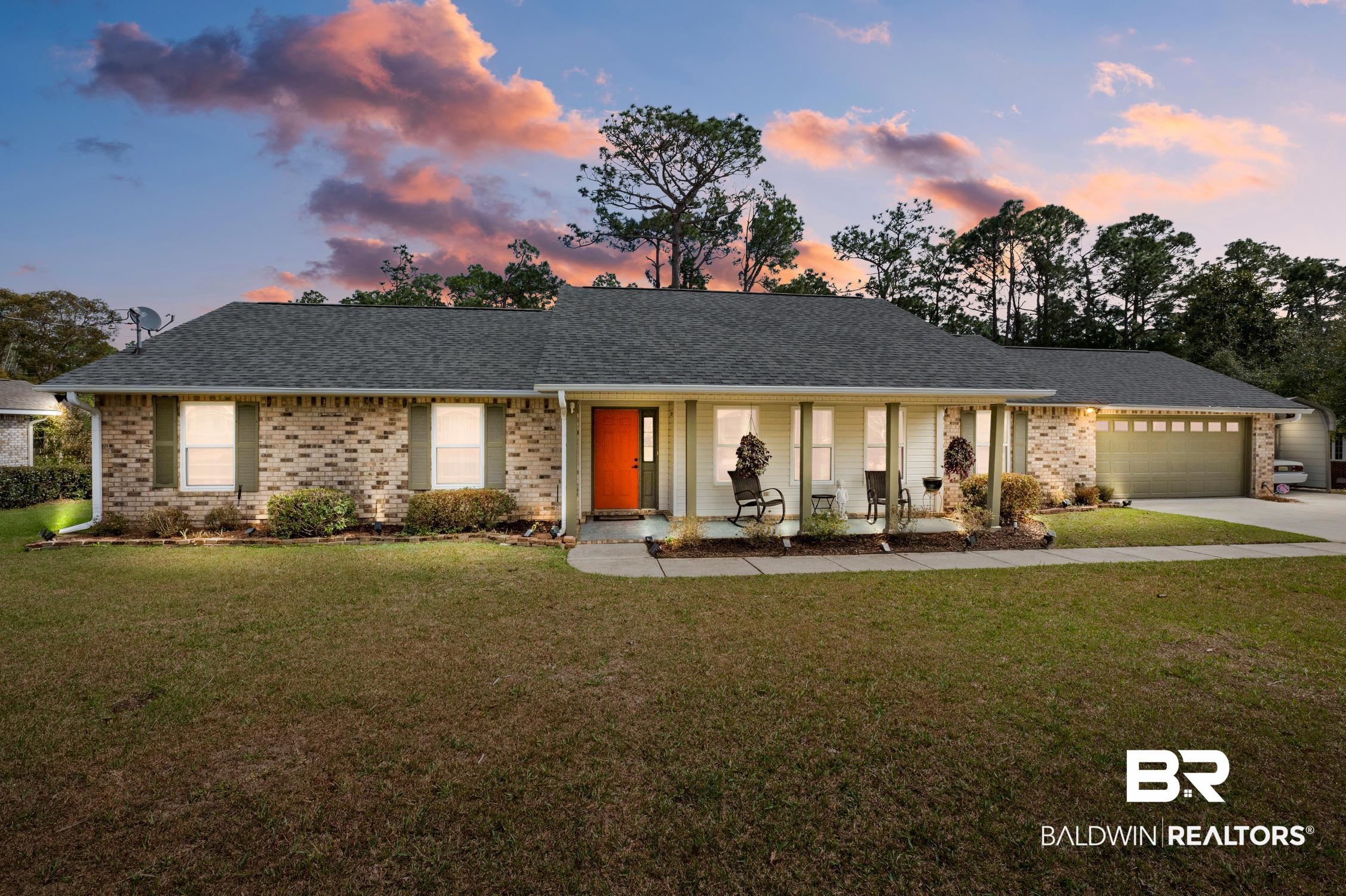 View of front of house featuring a porch, a front yard, driveway, and a garage
