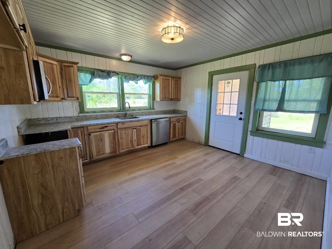 6464 Ridge Road Brewton, AL 36426 - Photo 7 of 14 Kitchen with wood finish cabinets, light wood finished floors, stainless steel appliances, wooden walls, and wooden ceiling