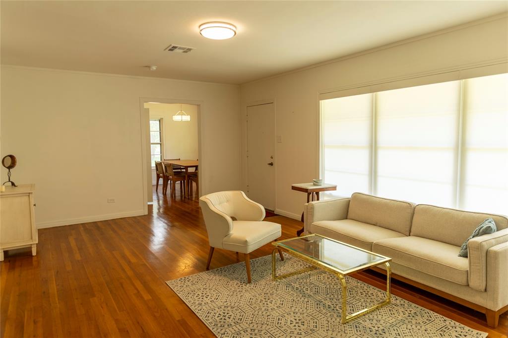 3228 Colcord Avenue Waco, TX 76707 - Photo 13 of 29 Living area featuring wood-finish flooring, a broad window with roller shades, and a flush-mount ceiling light