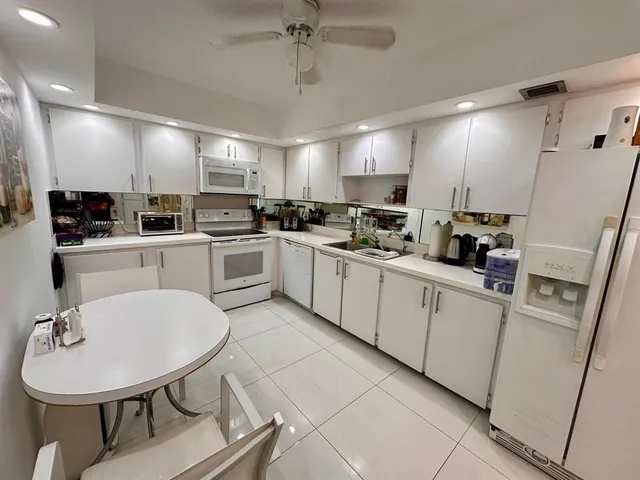 a kitchen with stainless steel appliances a sink a stove a refrigerator cabinets and chairs