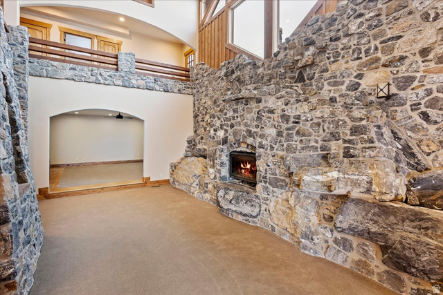 246 Woods Creek Road Morgan, UT 84050 - Photo 22 of 69 Extensive stone accent walls featuring a built-in fireplace, a stone-faced second-story railing with a wood top, and a recessed archway