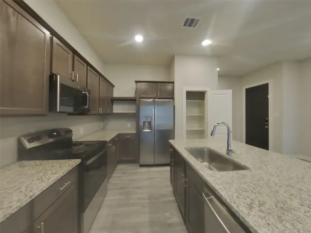 a kitchen with stainless steel appliances granite countertop a sink and a refrigerator