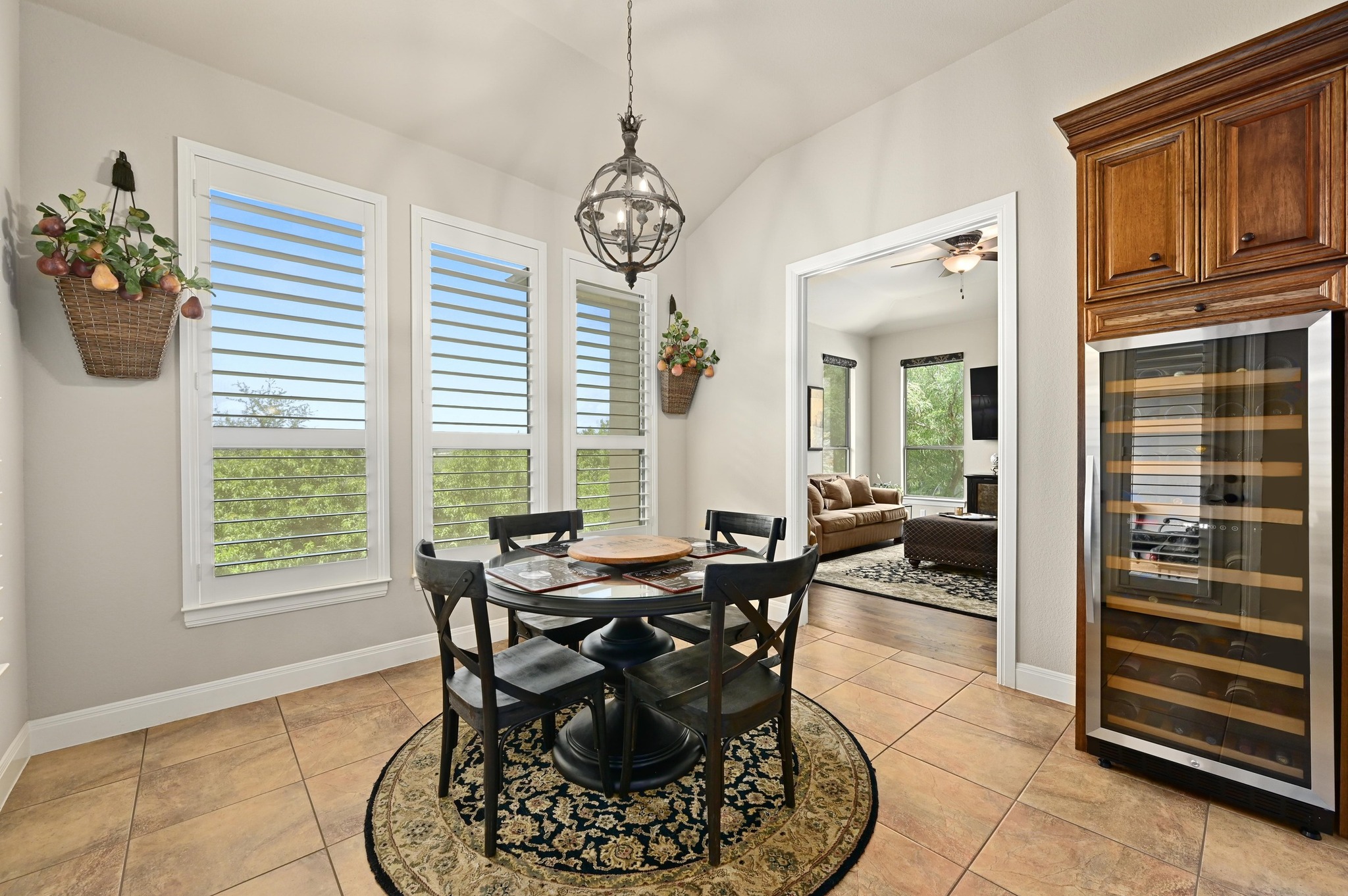 16129 Zagros Way Austin, TX 78738 - Photo 11 of 25 Kitchen Dining space featuring beverage cooler, lofted ceiling, suspended lighting, light tile patterned flooring, and a ceiling fan