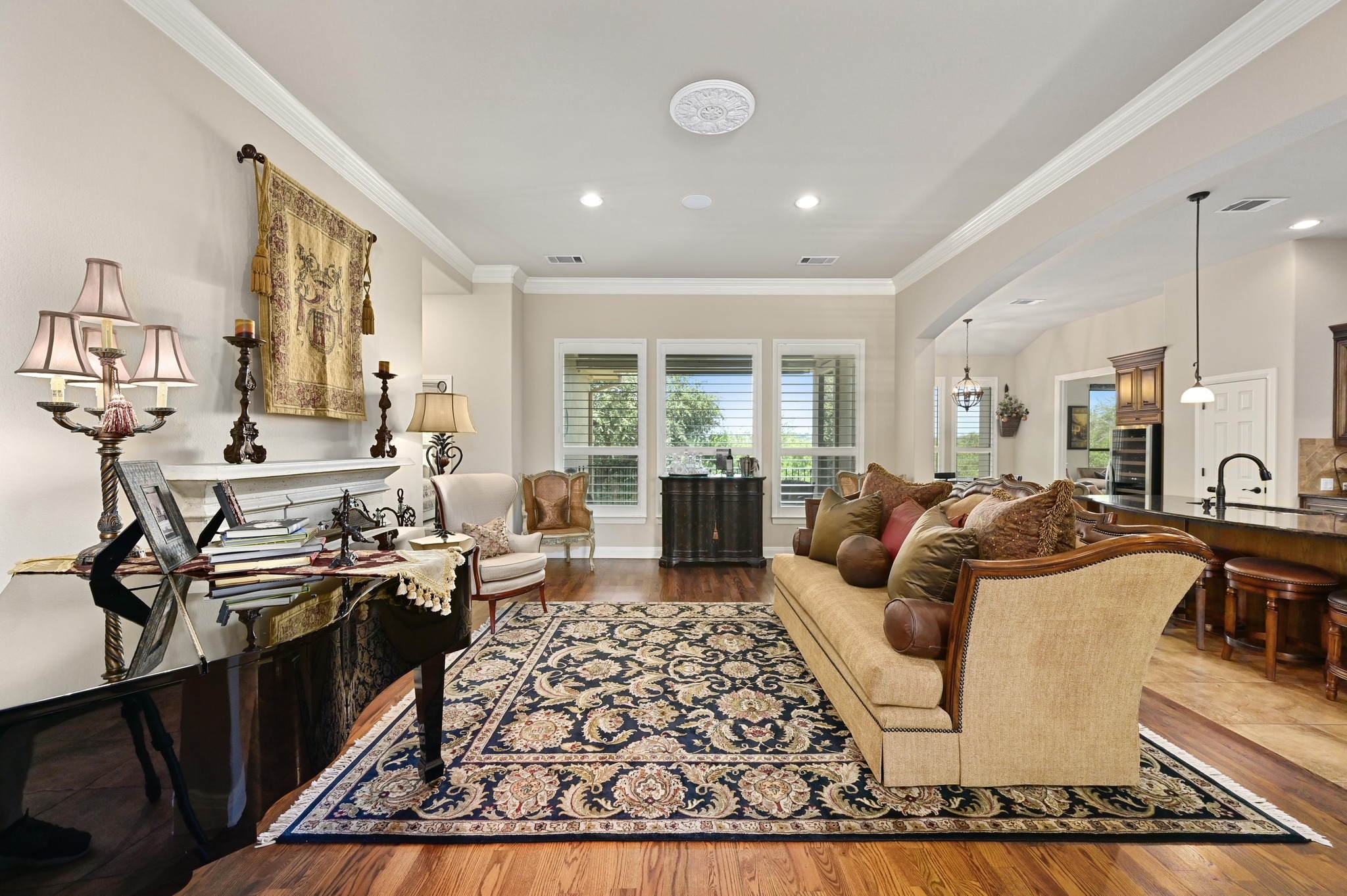 16129 Zagros Way Austin, TX 78738 - Photo 6 of 25 Living area featuring a fireplace, crown molding, wood flooring , plantation shutters.