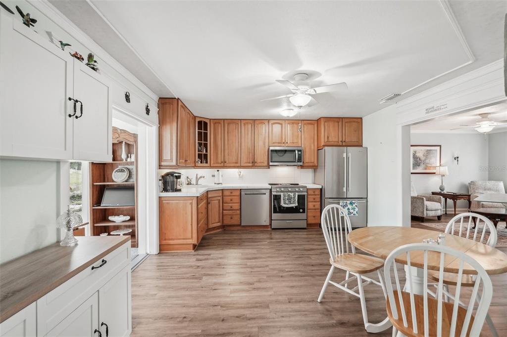 708 Rutgers Place Sun City Center, FL 33573 - Photo 10 of 27 a kitchen with stainless steel appliances a refrigerator a stove a sink dishwasher a dining table and chairs with wooden floor