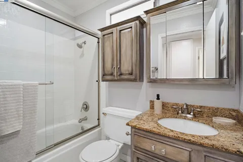 a bathroom with a granite countertop sink toilet a mirror and shower