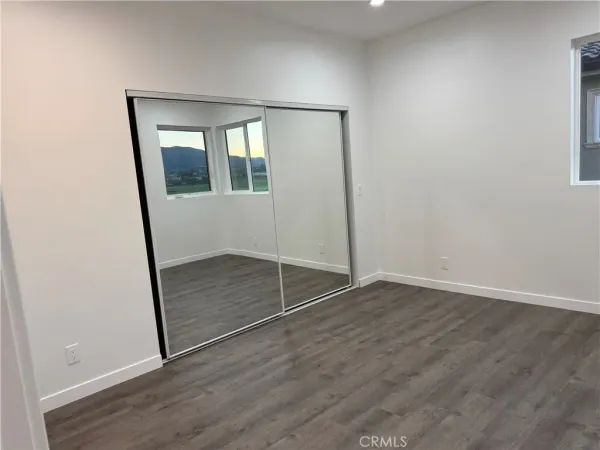 an empty room with wooden floor and mirror