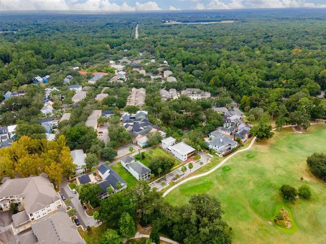 an aerial view of residential houses with outdoor space and trees