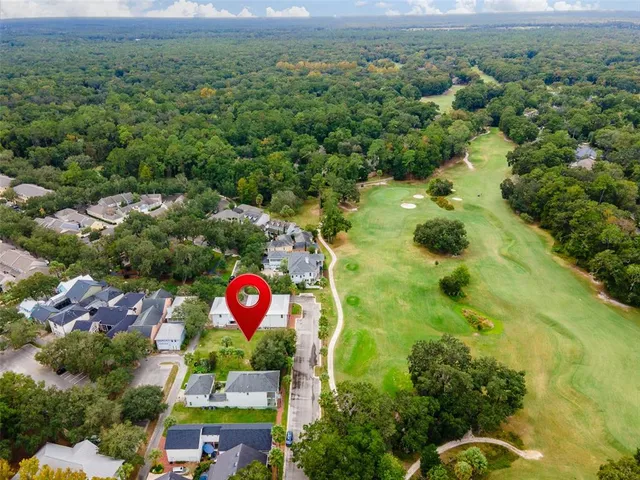 an aerial view of residential houses with outdoor space and trees