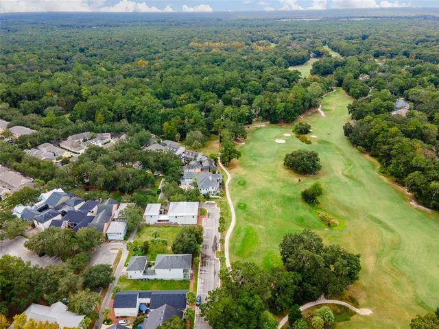 an aerial view of residential houses with outdoor space and trees