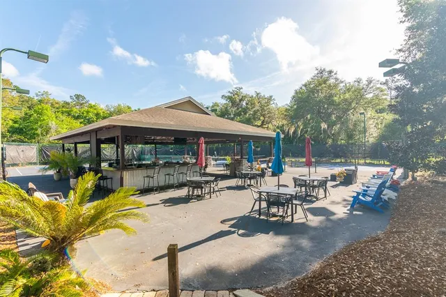 a view of a patio with table and chairs under an umbrella with large trees