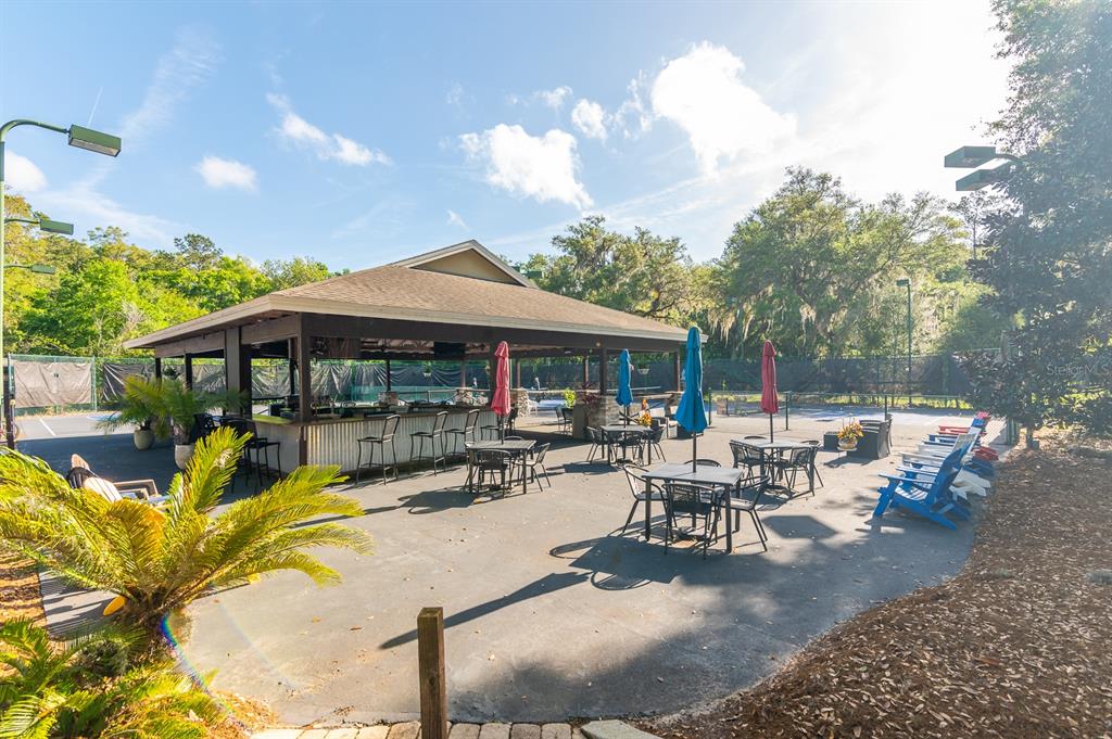 9139 Southwest 47 Place Gainesville, FL 32608 - Photo 37 of 41 a view of a patio with table and chairs under an umbrella with large trees
