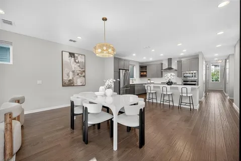 a dining room with wooden floor a chandelier a wooden table and chairs