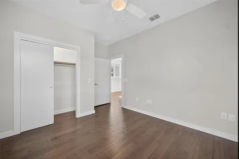 an empty room with wooden floor chandelier fan and windows