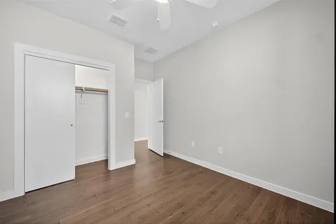 an empty room with wooden floor and fan