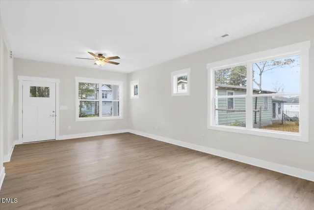 a view of an empty room with a window and wooden floor