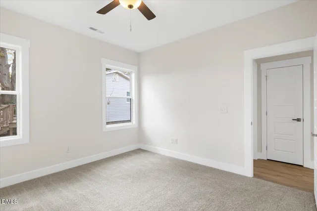 an empty room with chandelier fan and windows