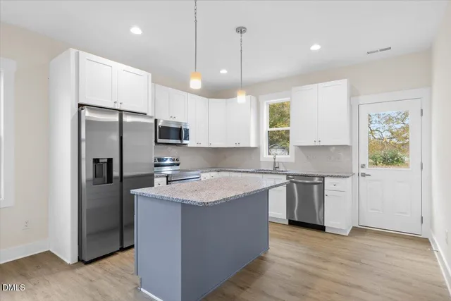 a kitchen with a sink a refrigerator a stove and wooden floor
