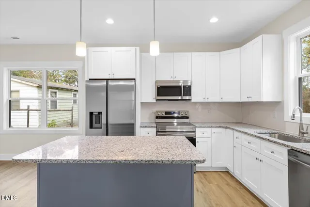 a kitchen with granite countertop a sink a center island stainless steel appliances and cabinets