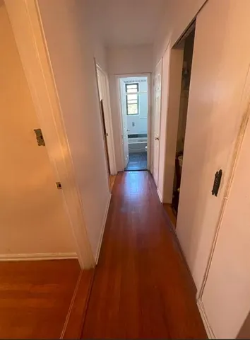 a spacious bedroom with a bed a couch and dresser with wooden floor