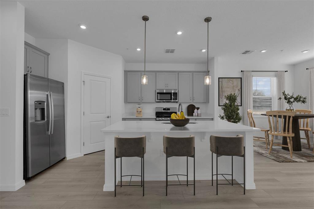 1812 Shadow Box Bend St. Cloud, FL 34771 - Photo 7 of 33 a kitchen view with stainless steel appliances kitchen island granite countertop a table chairs and a refrigerator
